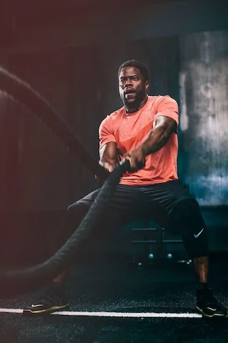 An athlete working out with battle ropes in a dark gym